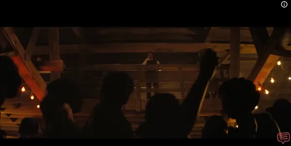 A person stands on a balcony addressing a crowd below.