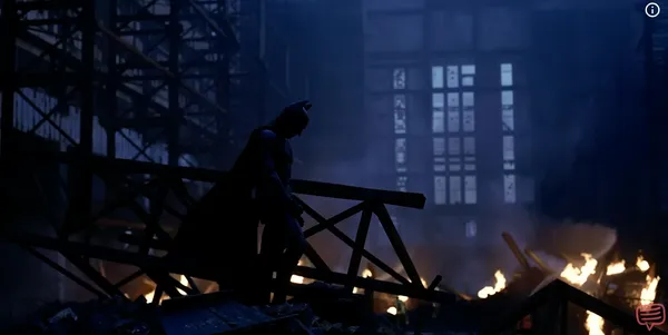 A lone figure silhouetted against flames in a dark, industrial setting.