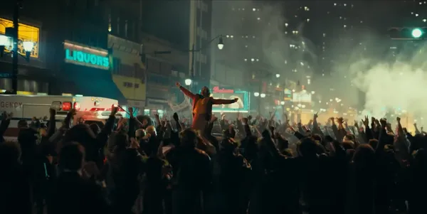 A person triumphantly stands in a crowd with raised arms amidst city chaos.