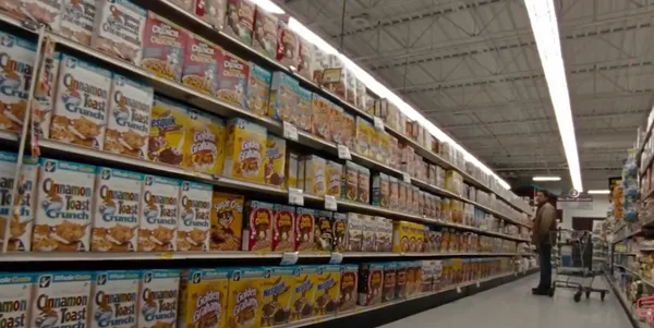 A person browsing cereal in a grocery aisle.