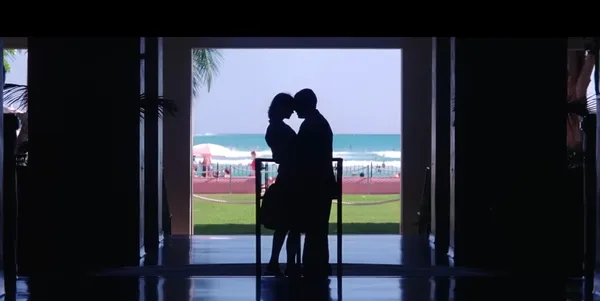 Silhouette of a couple kissing with a bright seascape backdrop.