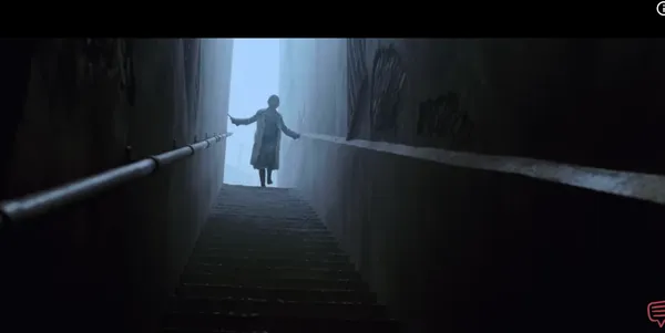 A lone figure descends a dimly lit staircase.