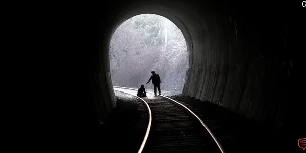 Silhouetted figures in a tunnel with light in the distance.
