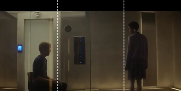 Two people facing each other separated by glass walls.