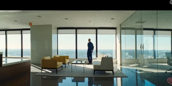 A person stands in a modern office space overlooking a cityscape.