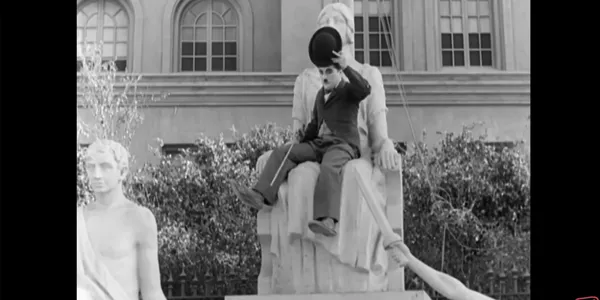 A person humorously sitting on a large statue.