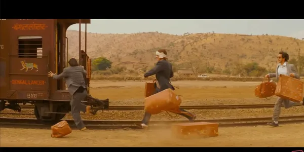 Three men in suits are running to catch a moving train with luggage.