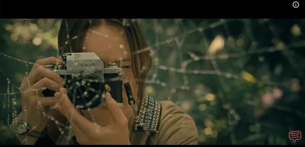 Photographer framing a shot through a dew-covered spider web