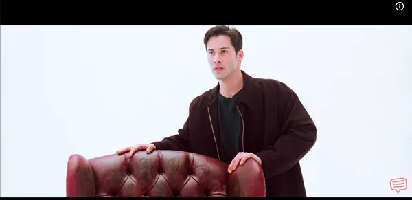 A man in a trench coat examines a red chair in a void