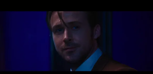 A man's face illuminated by moody blue and purple neon light