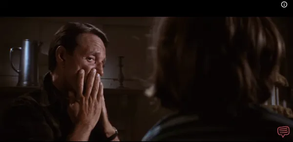 A man looking horrified while covering his mouth with both hands in a dim room