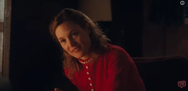 A woman warmly smiling at someone out of frame in a cozily lit space