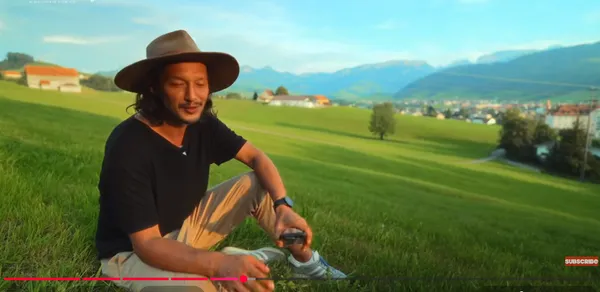 Person sitting in a scenic hilly landscape.