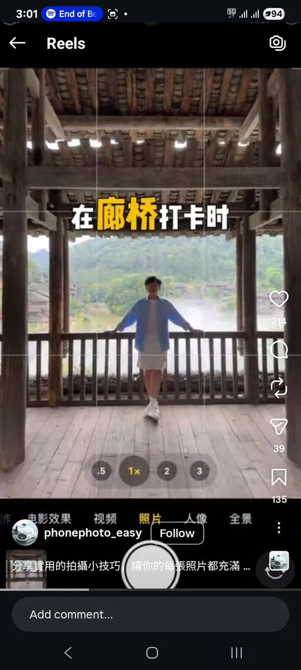 Person standing on a wooden balcony overlooking a scenic backdrop.