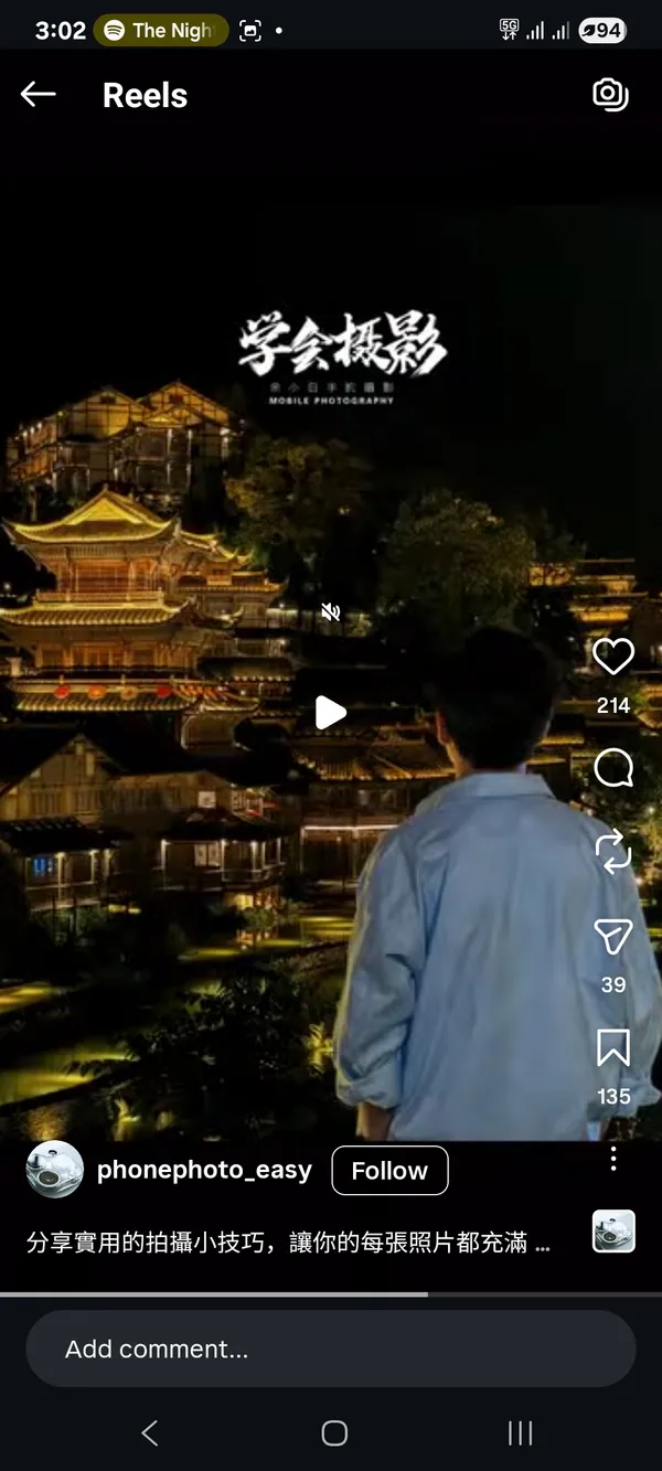 A person viewing an illuminated traditional building at night.
