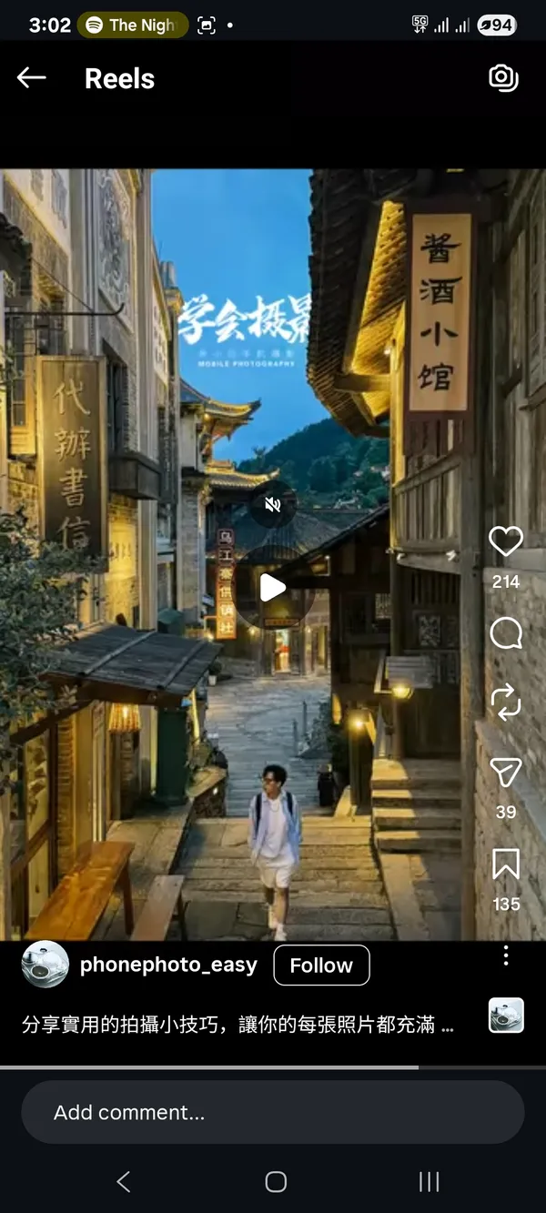 A person walking through a traditional narrow street with illuminated signs.