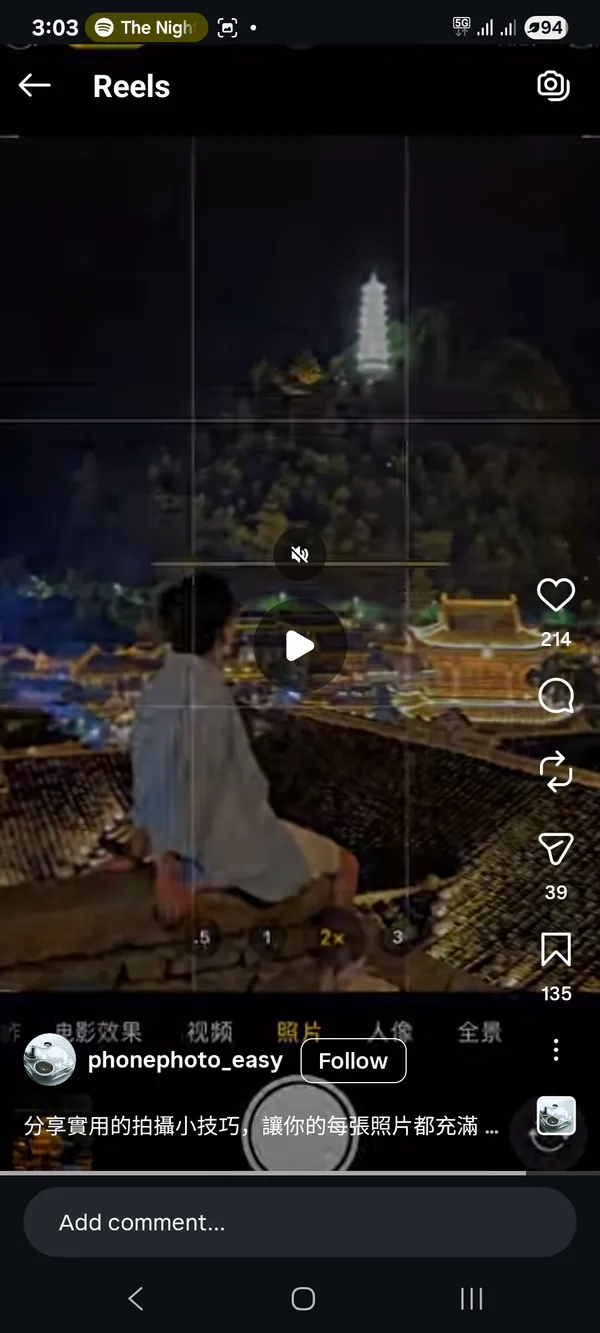 Person sitting with illuminated tower in the background at night.