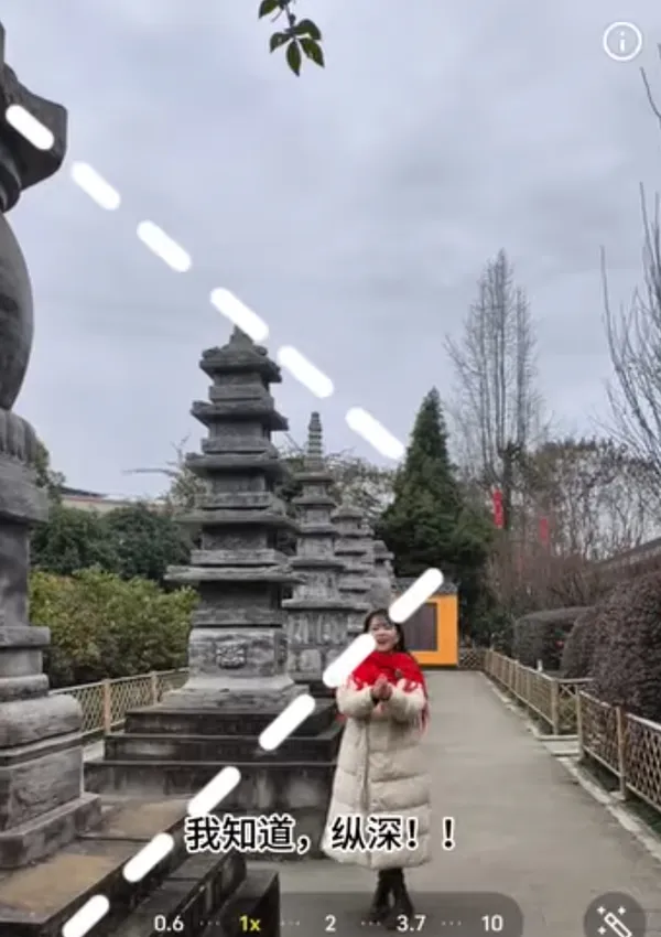 Person posing in front of stone structures in a garden.