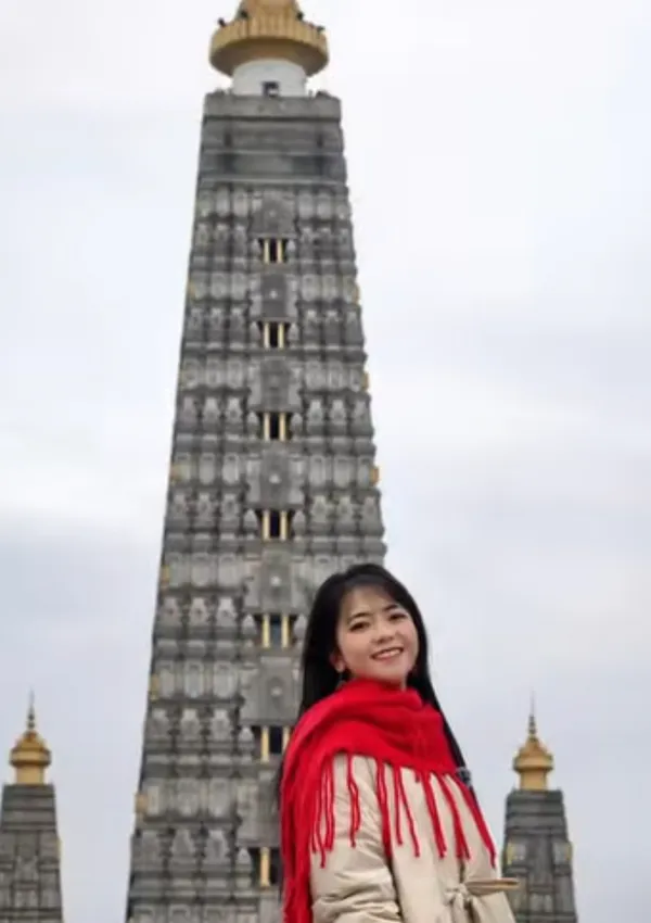 A person standing in front of a tall, ornate tower.