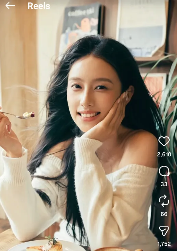 A person smiling while holding a dessert in a cozy setting.