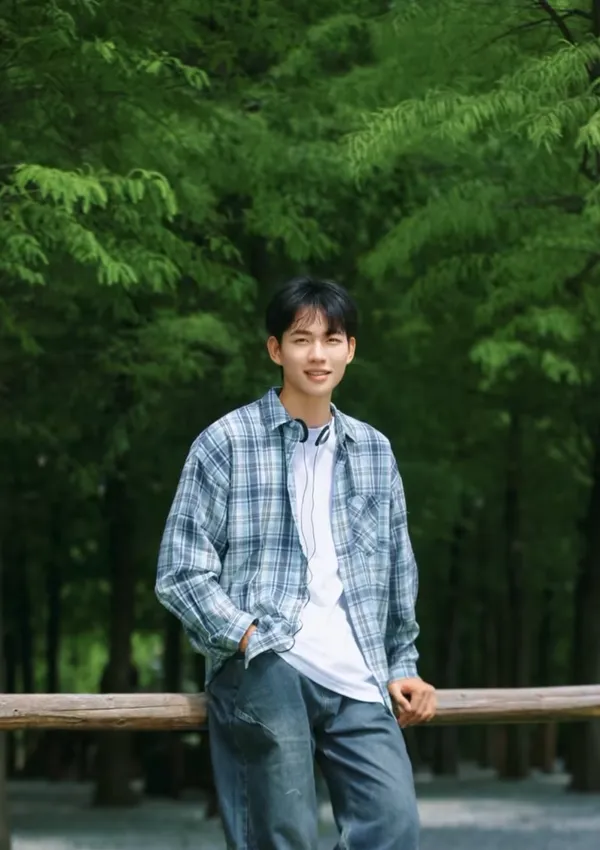 Person standing in a lush green outdoor setting.