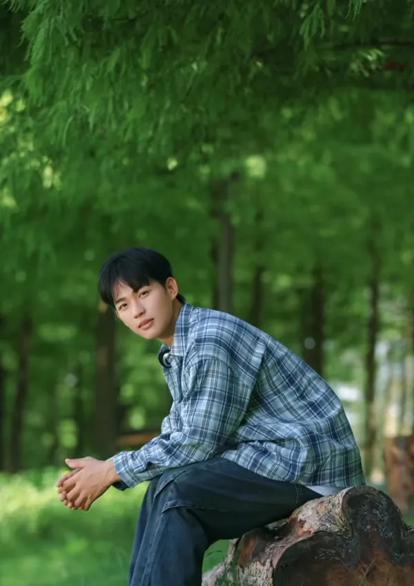 A person sitting on a log in a lush green forest.