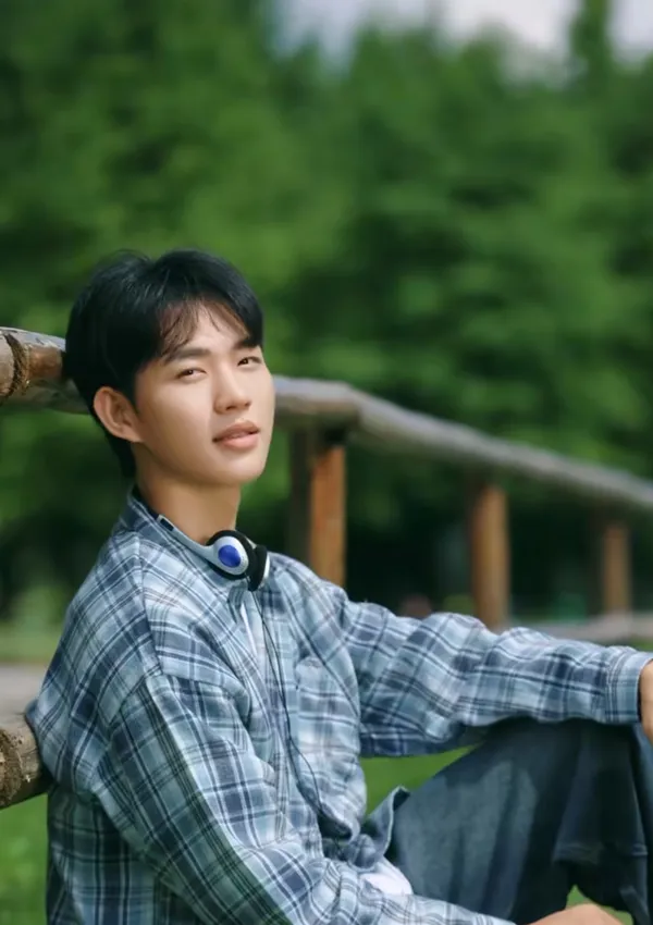 A young person relaxing outdoors with headphones around their neck.