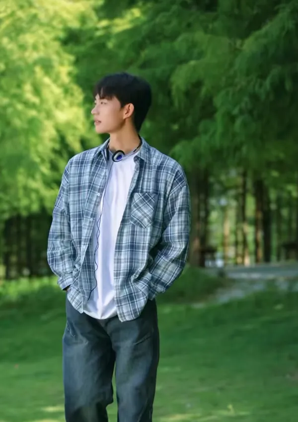 A person standing outdoors surrounded by greenery.