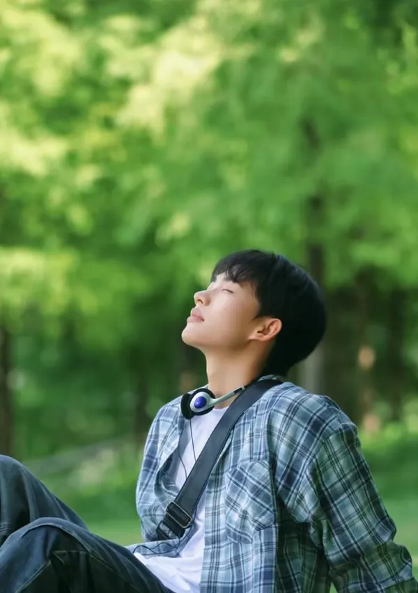 A person relaxing outdoors, enjoying nature with closed eyes.