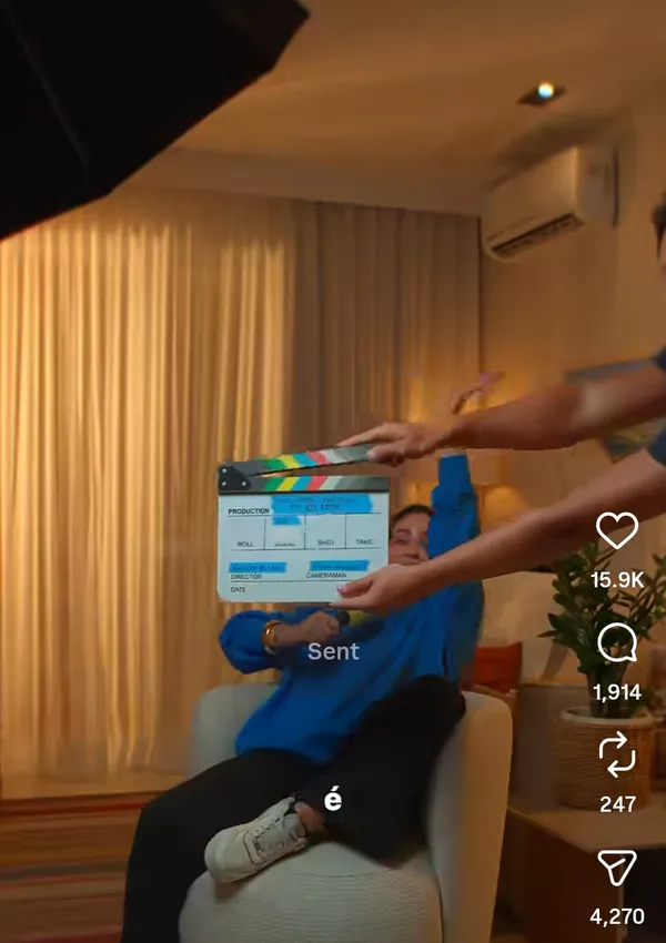 A clapperboard is about to be snapped in a casual indoor setting.