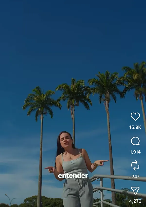 Person standing outdoors with palm trees in the background.