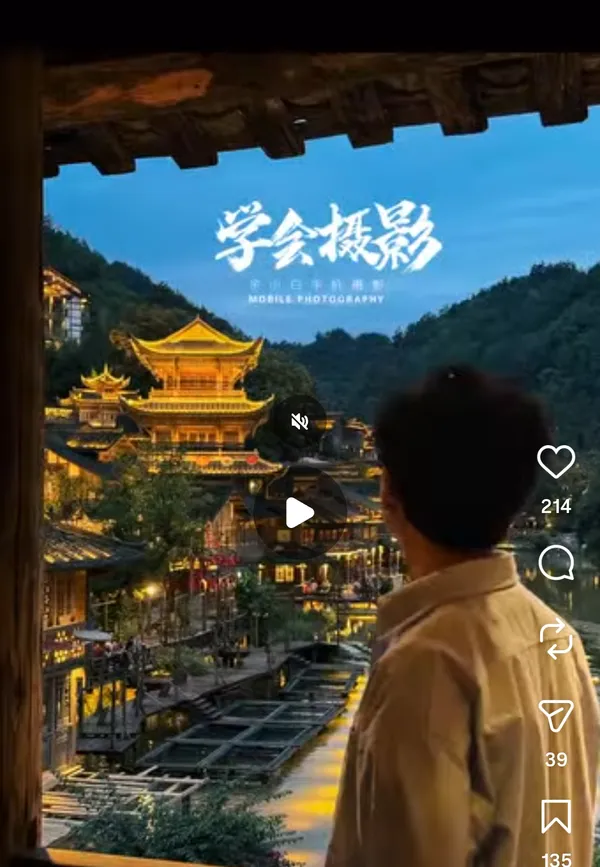 A person gazes at a beautifully lit traditional village during twilight.